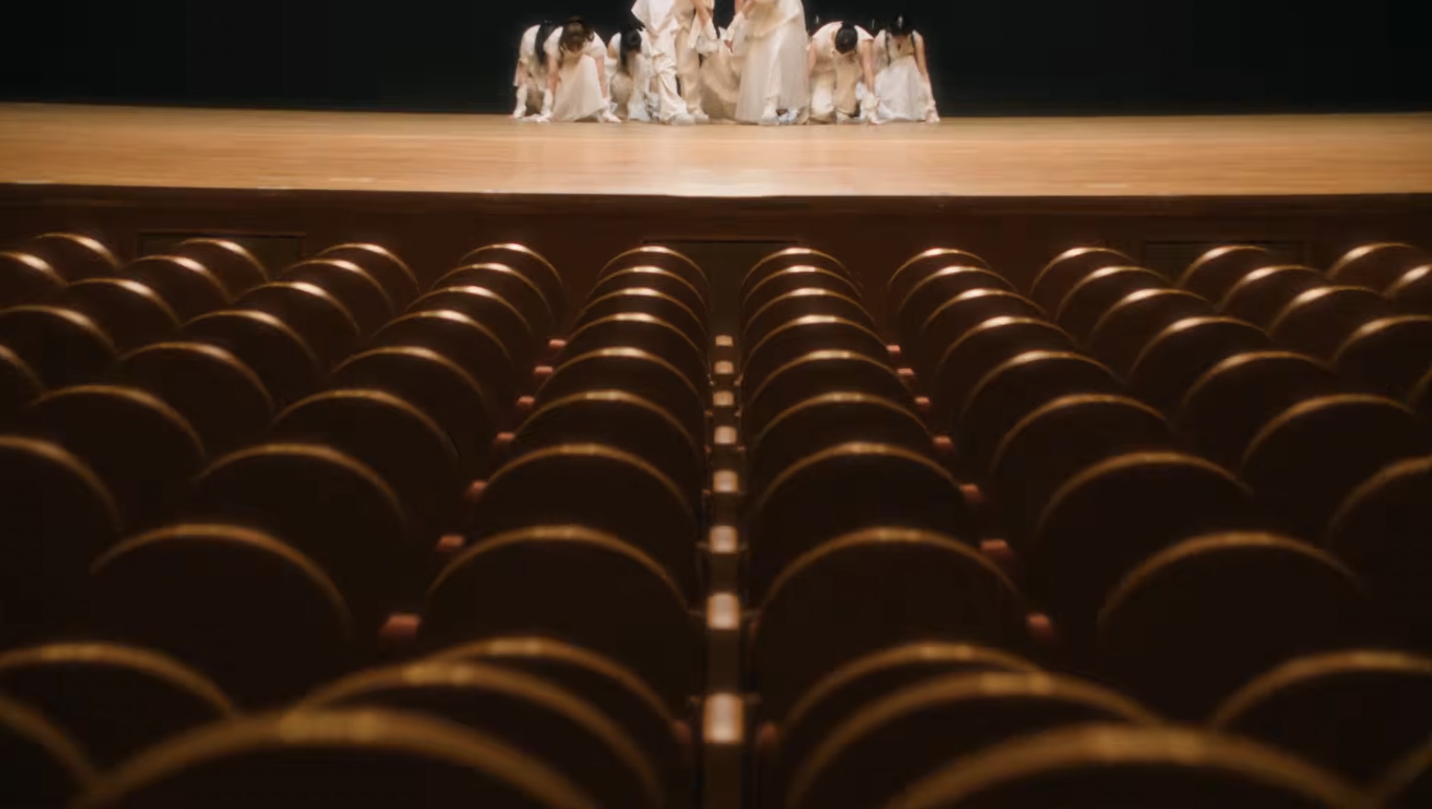 櫻坂46『自称バレエダンサー』MVの誰も座っていない客席と、白い衣装のメンバーが身を低くした舞台