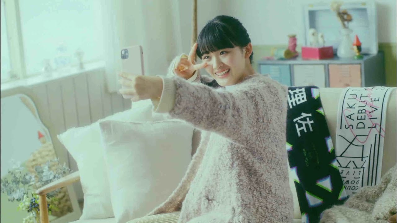 スマートフォンに向けて笑顔でピースする女性